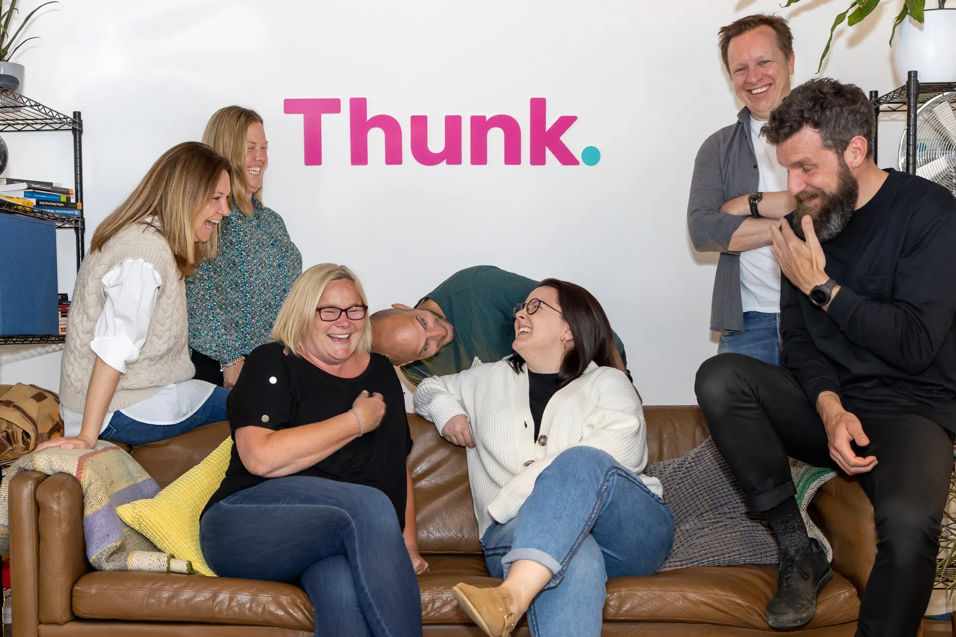 A group of people sat on a sofa laughing
